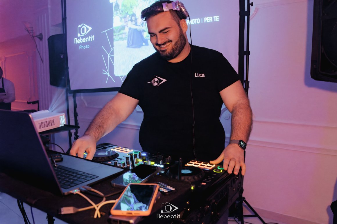 DJ al lavoro sulla console, tra luci viola e blu.