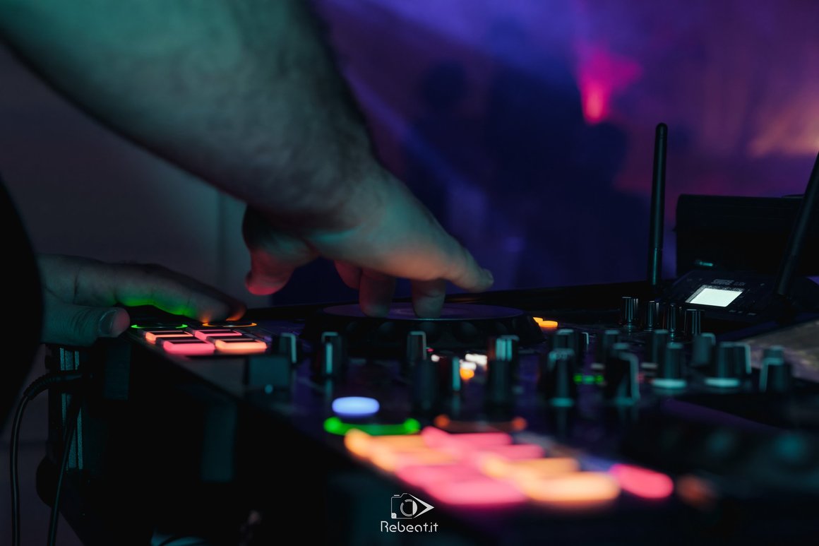 Dettaglio delle mani sulla console illuminata durante una serata.