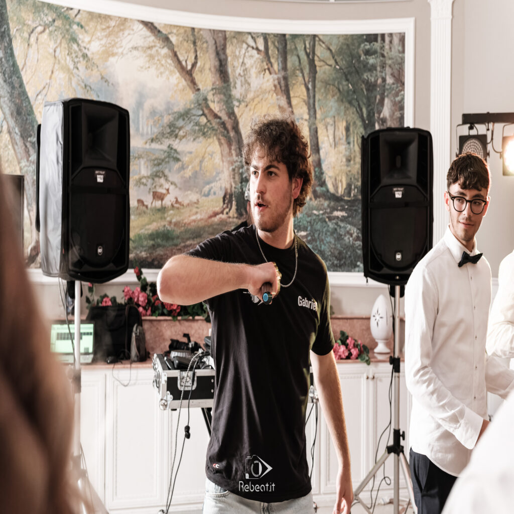 Animatore con microfono e DJ durante un evento in sala.