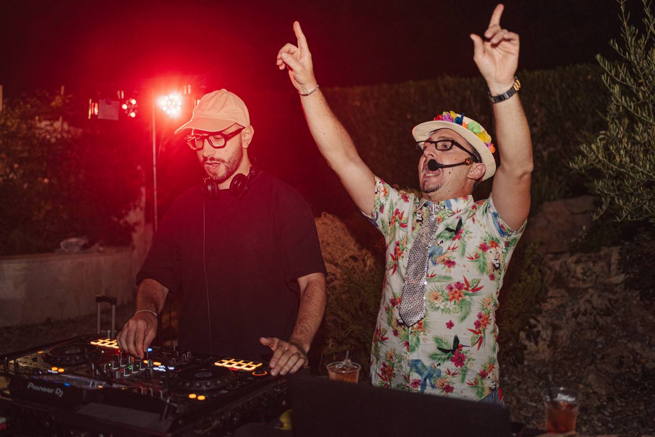DJ e animatore alla console durante una festa all’aperto, con luci rosse.