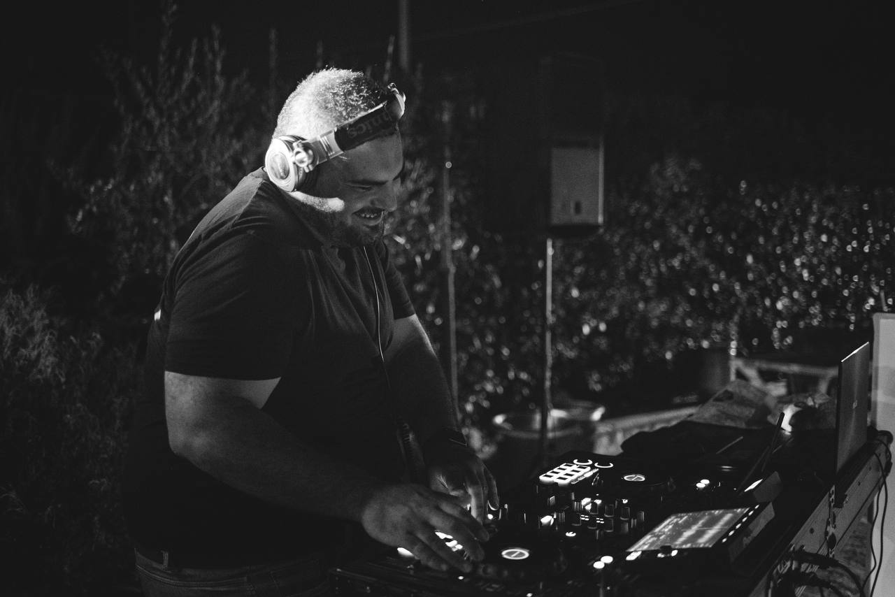 DJ alla console durante una serata all’aperto, in una fotografia in bianco e nero.